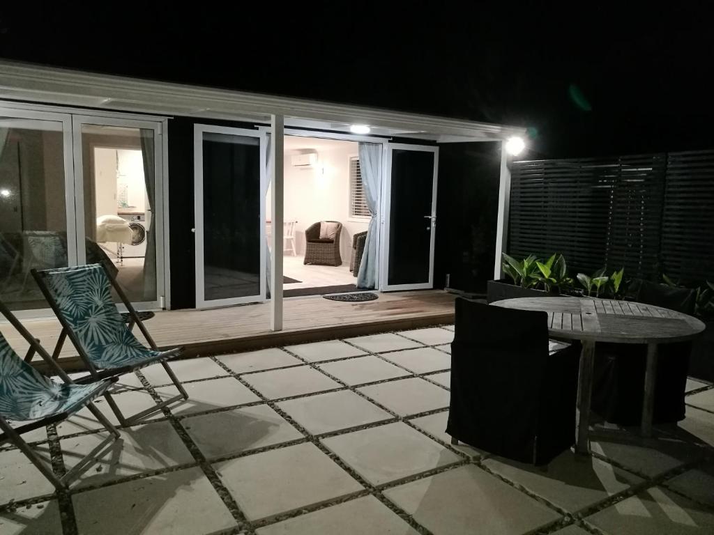 eine Terrasse mit 2 Stühlen, einem Tisch und einem Zimmer in der Unterkunft Terra Nostra in Mapua