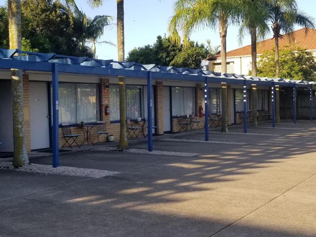 a row of buildings with blue poles and palm trees at Raceways Motel in Brisbane