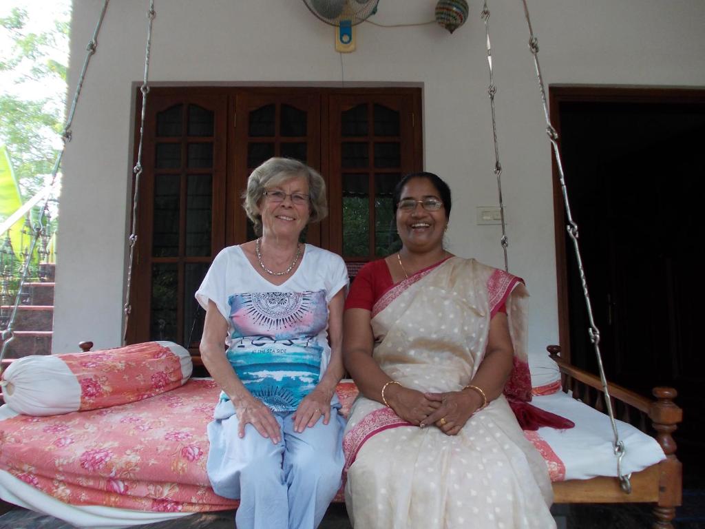 two older women sitting on a porch swing at Palakal Residency in Cochin