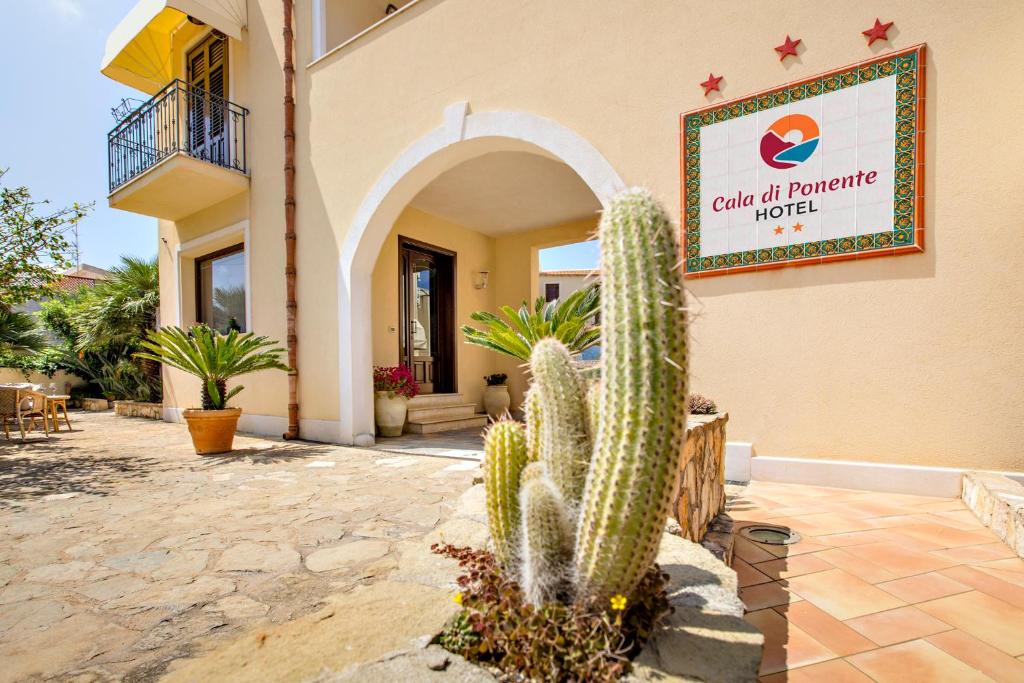 een cactus voor een gebouw met een bord bij Cala di Ponente in Castelluzzo