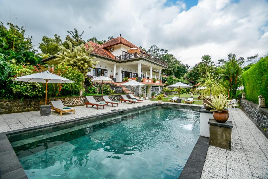 a house with a swimming pool in front of a house at Bukit Asri Lodge in Seraya