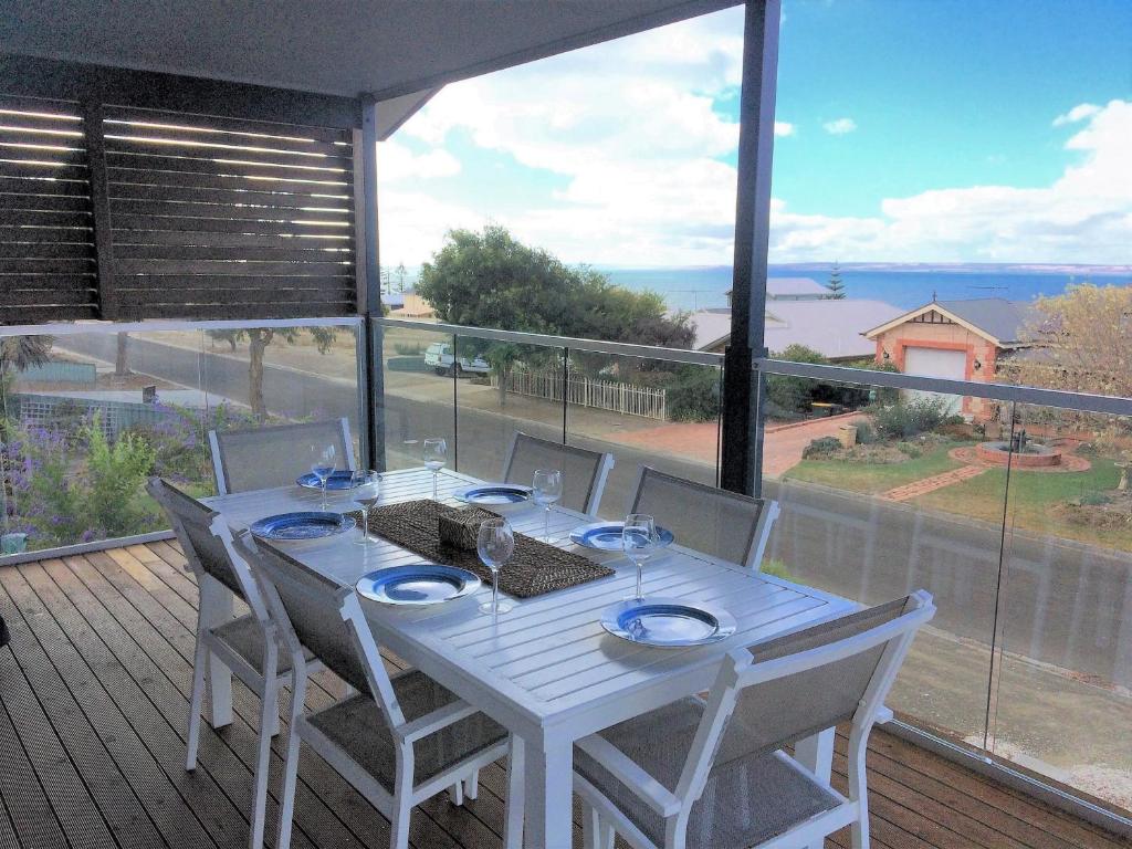a white table and chairs on a deck with a large window at Bayview Beach House Apartment No 2 in Kingscote