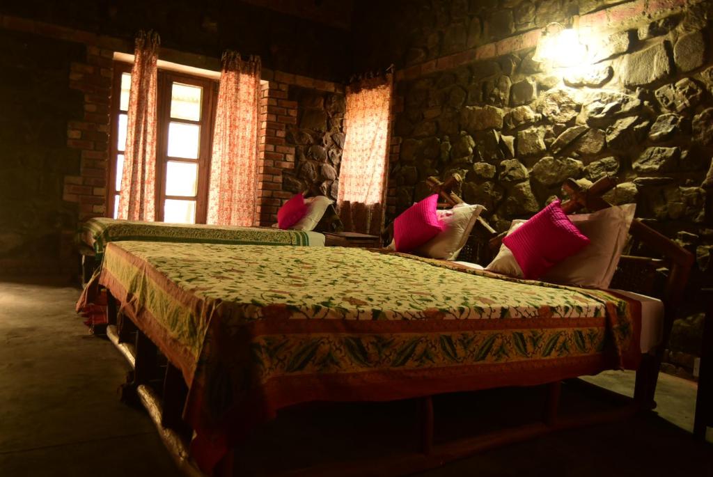 a bedroom with two beds and a stone wall at Wild Brook in Rishīkesh