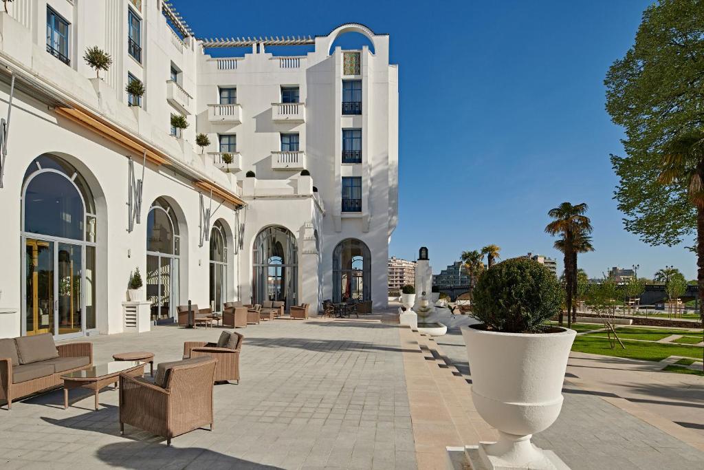 a large white building with chairs and a courtyard at Hotel &amp; Spa Vacances Bleues Le Splendid in Dax