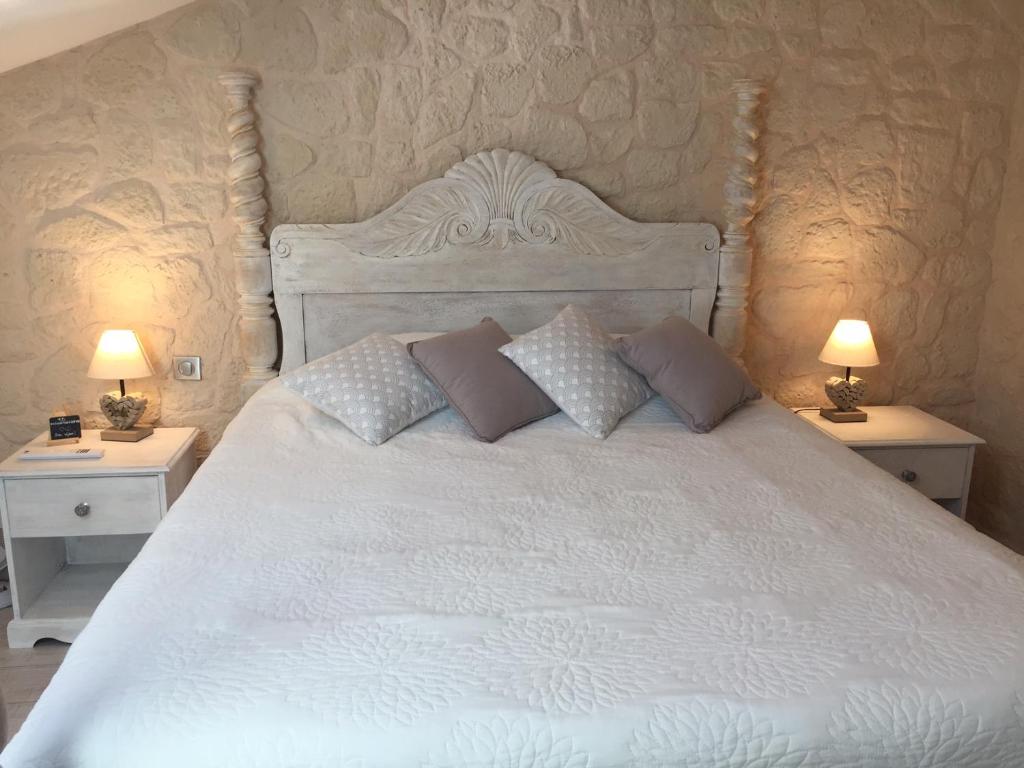 1 cama blanca con almohadas y 2 mesitas de noche en Guesthouse Le Pujol, en Sainte-Foy-dʼAigrefeuille