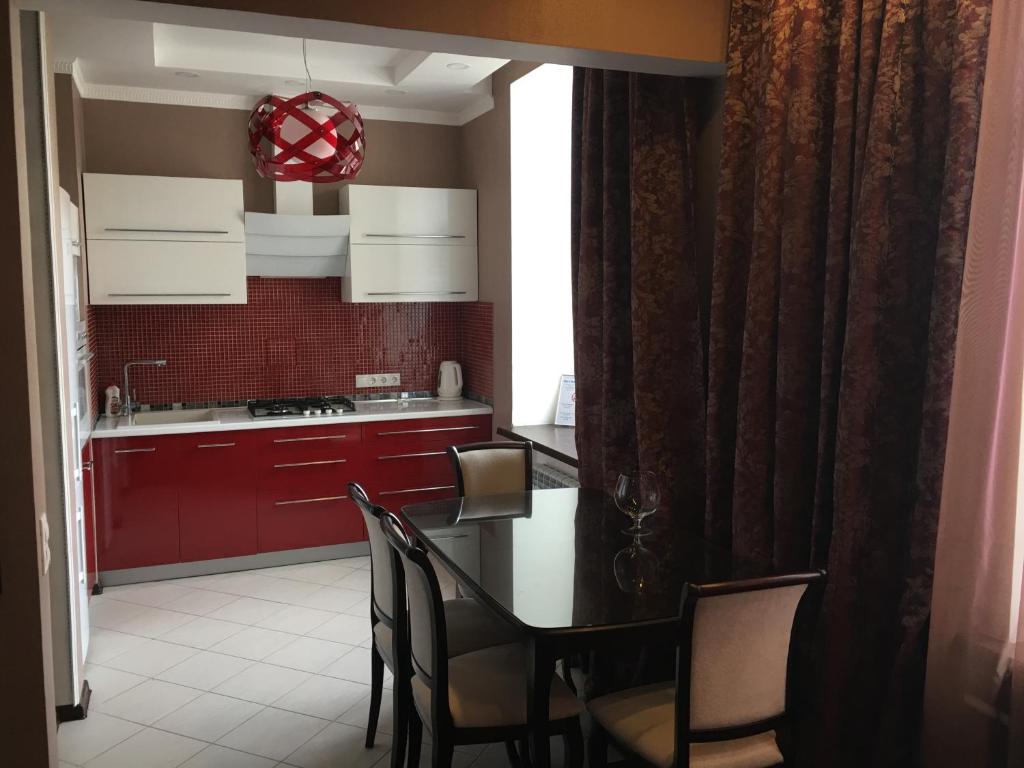 モスクワにあるCosy-4 Apartments na Kievskayaのキッチン(赤いキャビネット、テーブル、椅子付)