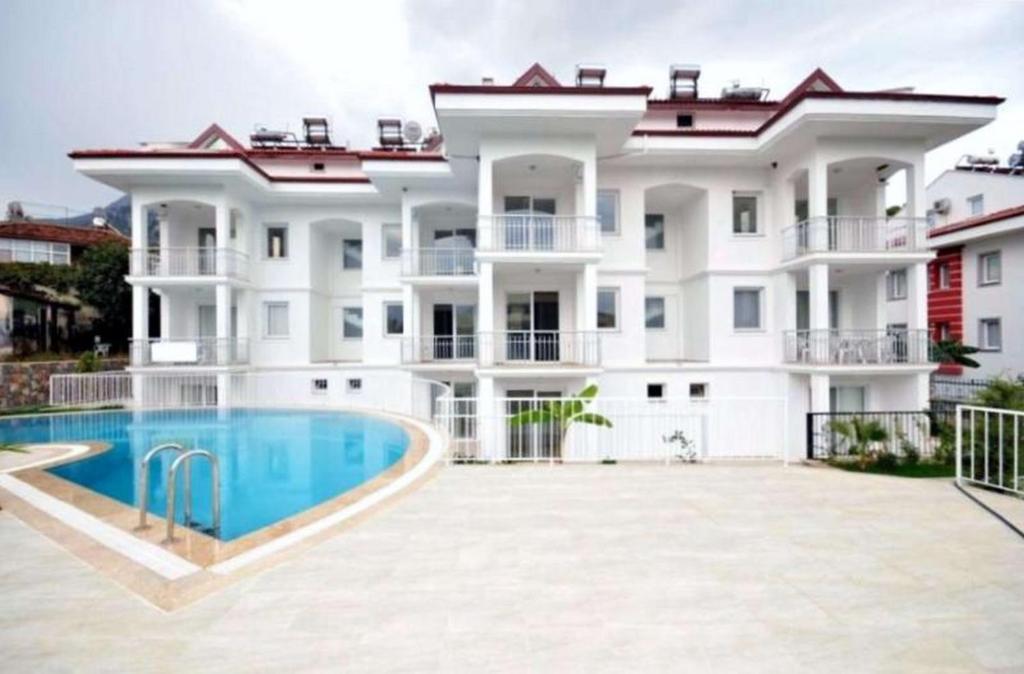 a large white apartment building with a swimming pool at Infinity Olympia Apartments in Oludeniz