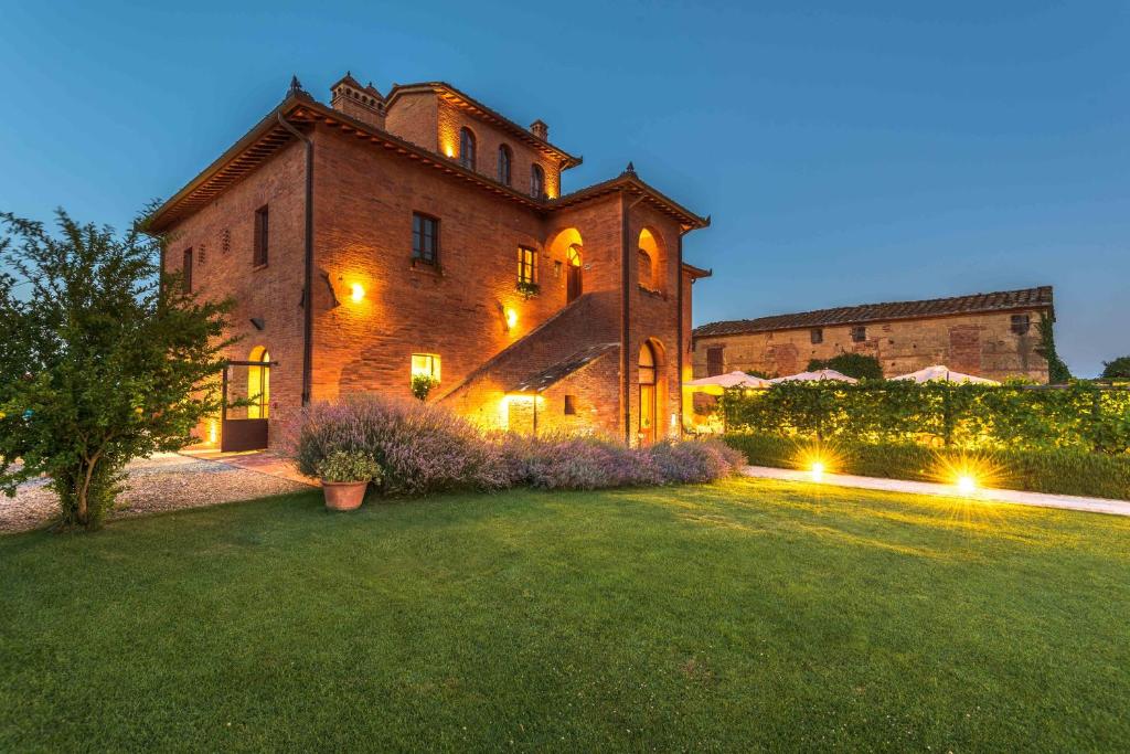 a large brick building with lights in a yard at Relais la Leopoldina in Bettolle