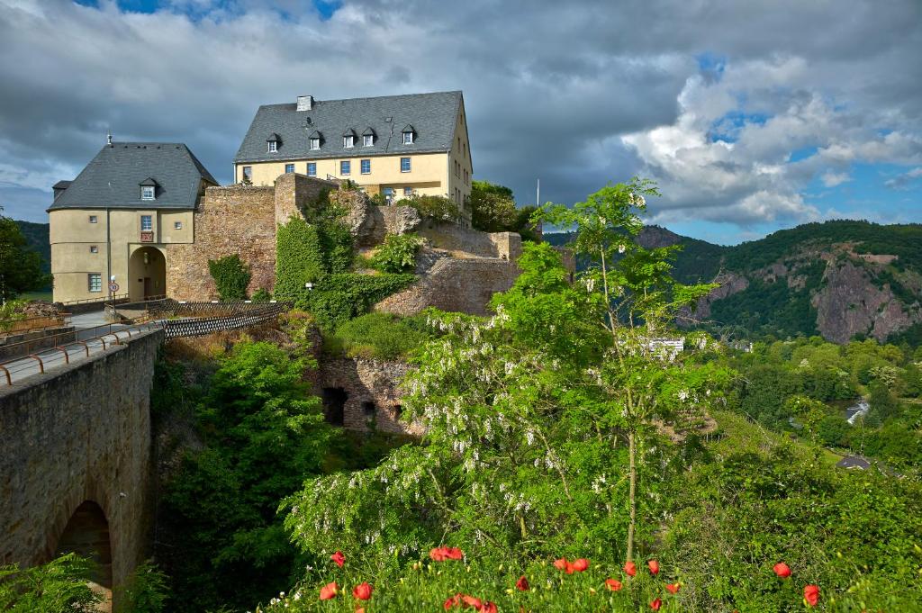 un castillo en la cima de una colina con flores en Ev.Familienferien-und Bildungsstätte Ebernburg en Bad Münster am Stein-Ebernburg