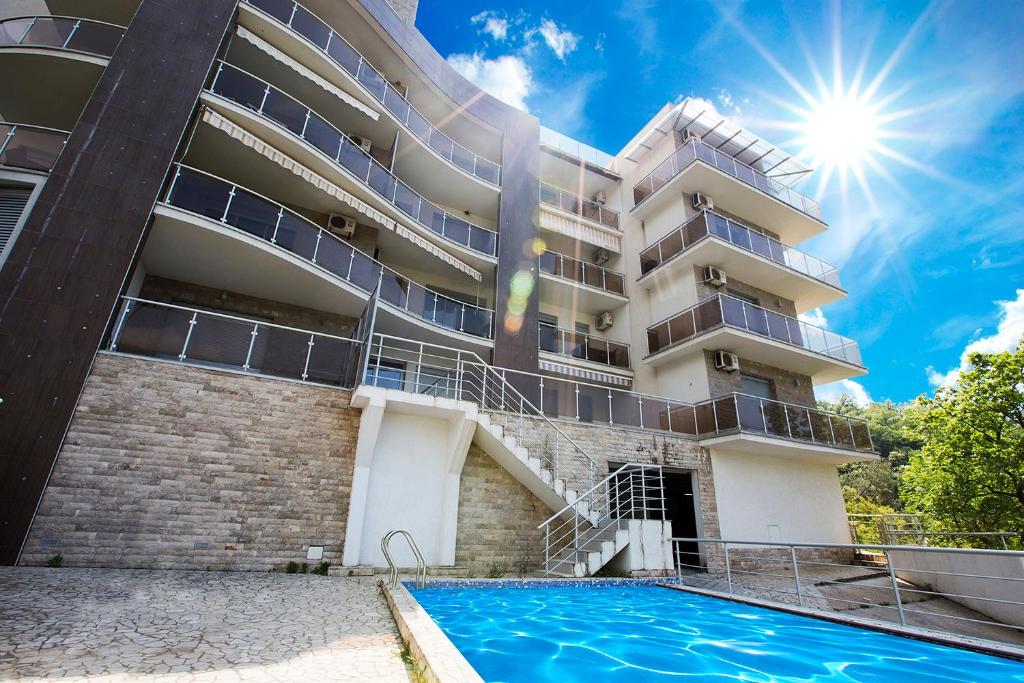 an apartment building with a swimming pool in front of it at Sea view Apartments Panorama Przno in Sveti Stefan
