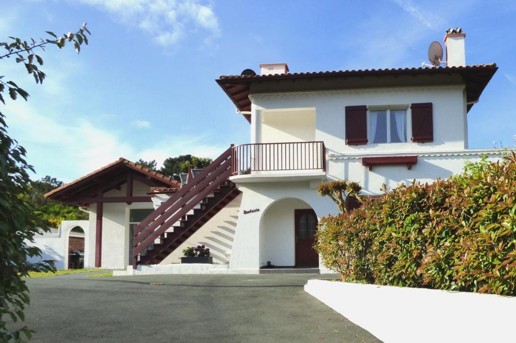 a white house with a balcony at Location Fantaisie Ondres in Ondres