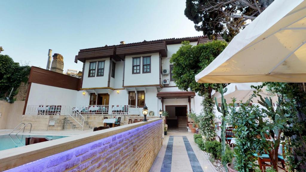 a house with a swimming pool and an umbrella at Urcu Hotel in Antalya