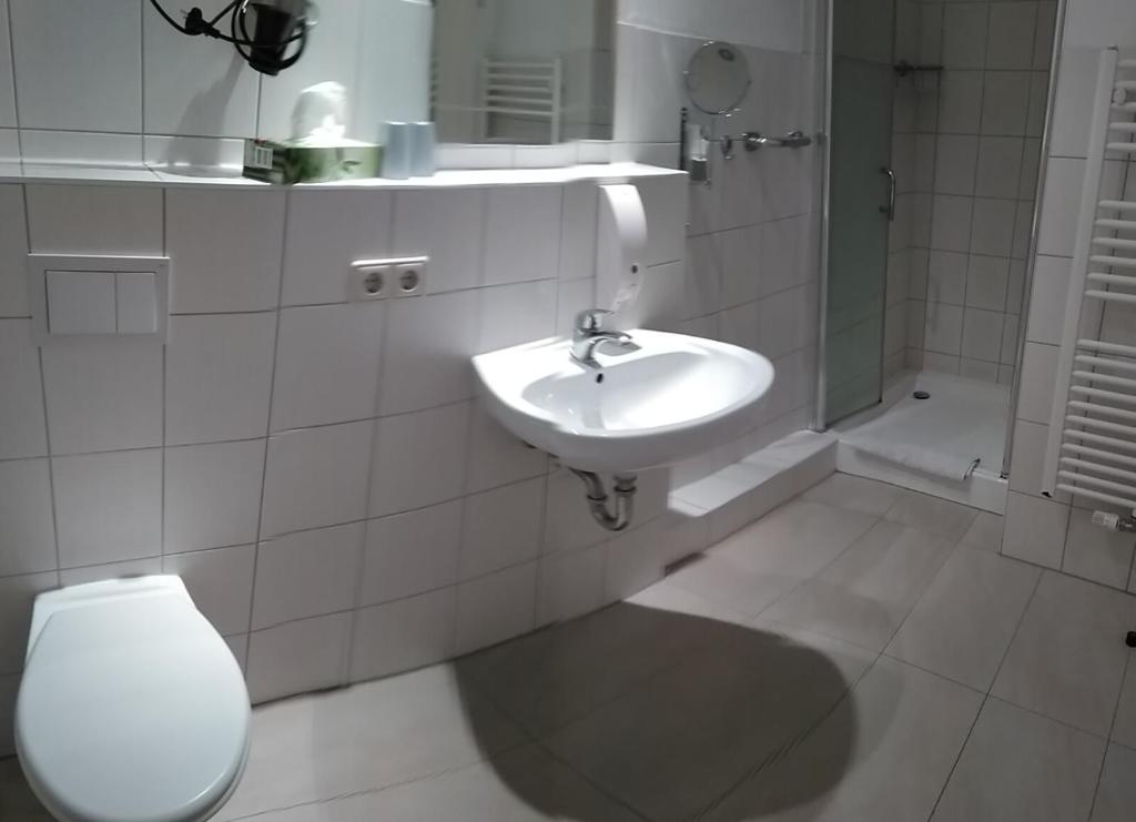 a white bathroom with a toilet and a sink at Pension Celia in Wismar