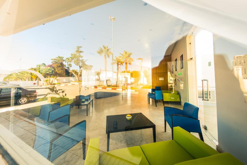 a view of a room with a table and chairs at Suites Hotel Mohammed V by Accor in Al Hoceïma