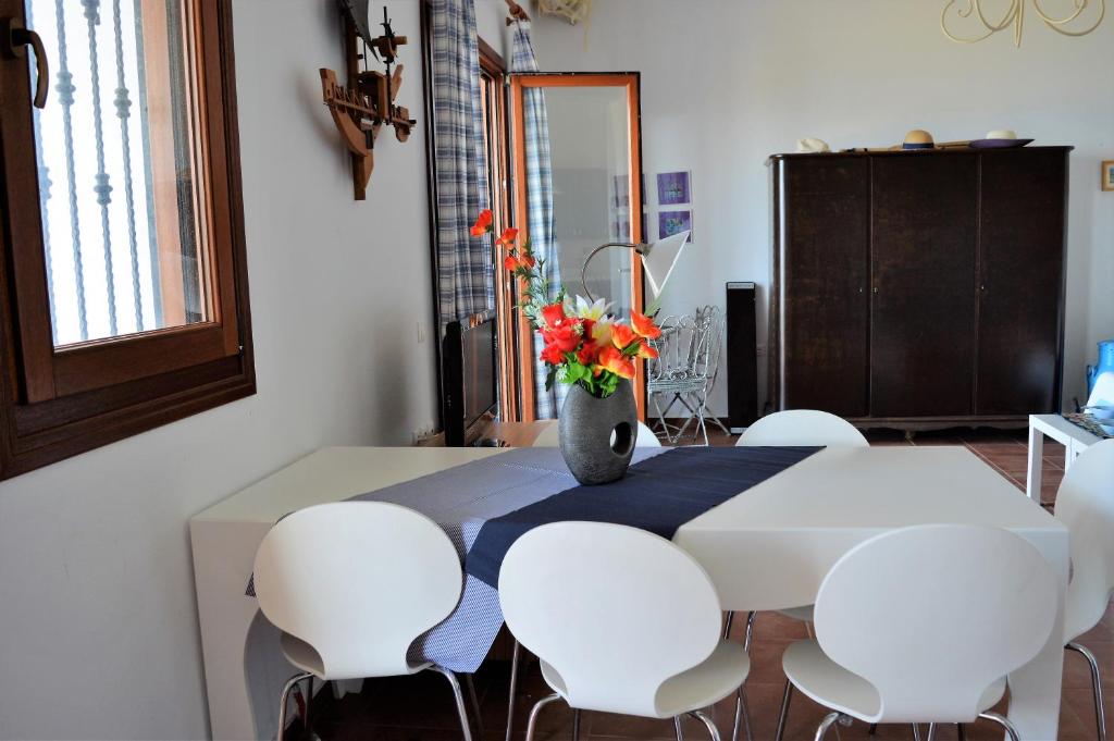 a dining room table with white chairs and a vase with flowers at Marvelous Sea View Eco Apt in Ammouliani
