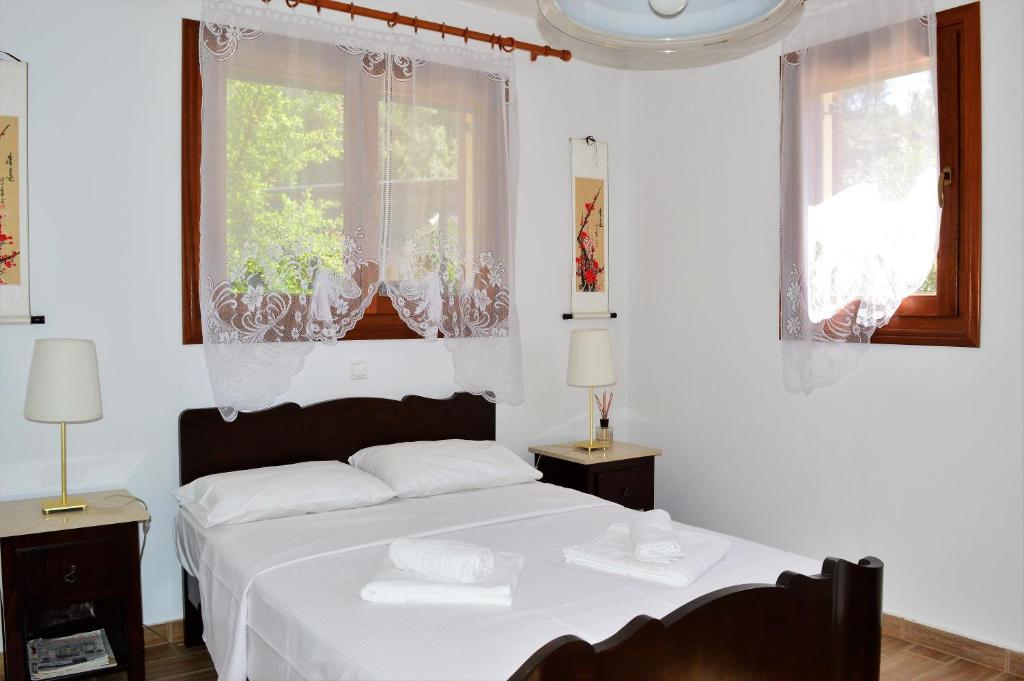 a white bedroom with a bed and two windows at Marvelous Sea View Eco Apt in Ammouliani