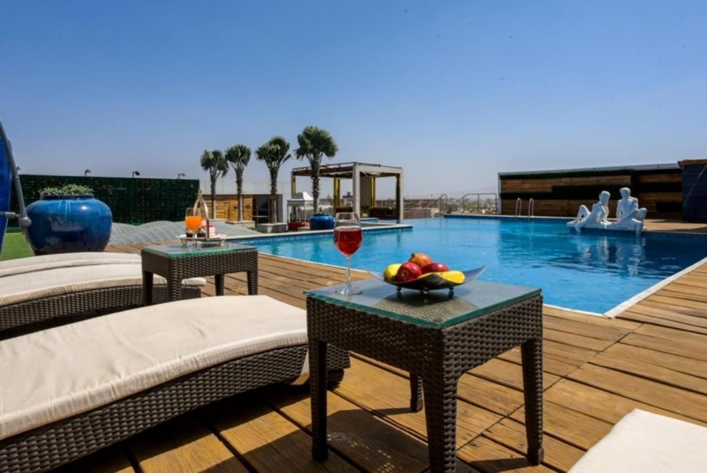 una piscina con dos mesas y un bol de fruta en ella en Shakun Hotels And Resorts, en Jaipur