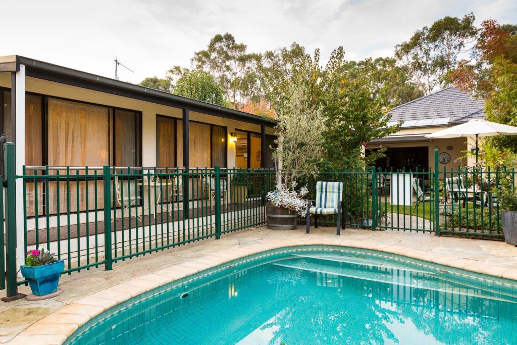 a swimming pool in front of a house with a fence at Courtsidecottage Bed and Breakfast in Euroa