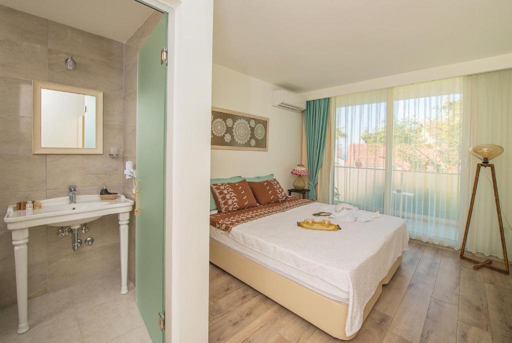 a bedroom with a bed and a sink and a window at Destina Hotel in Çeşme
