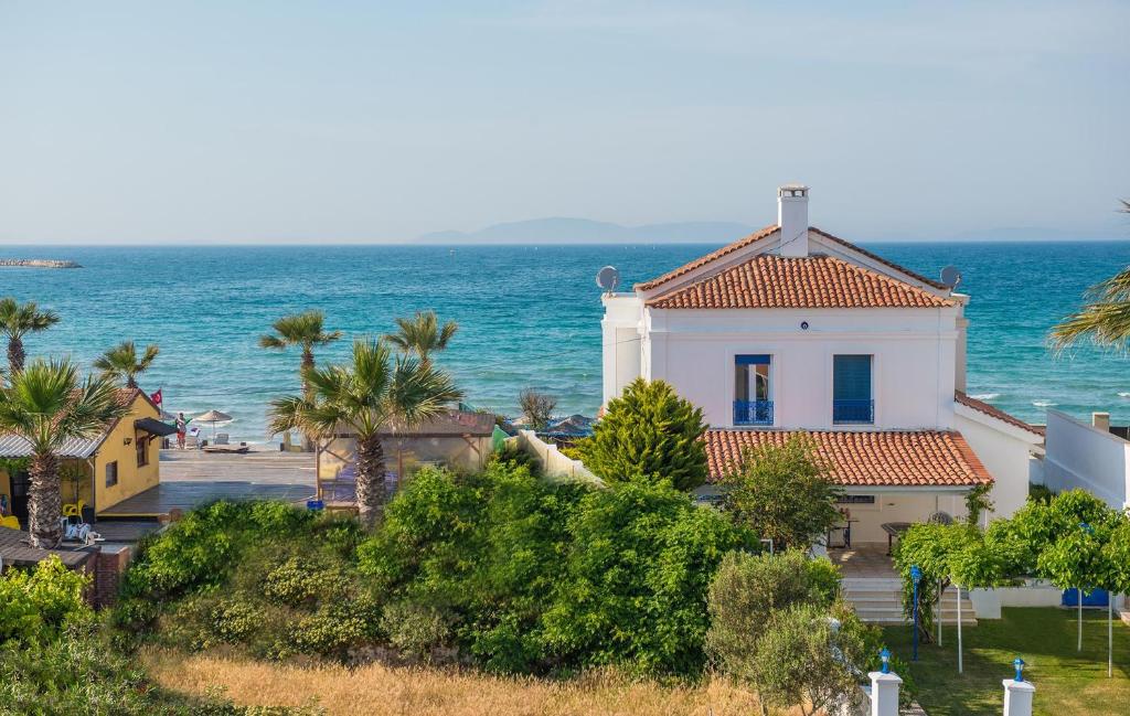 a white house with a red roof next to the ocean at Destina Hotel in Çeşme