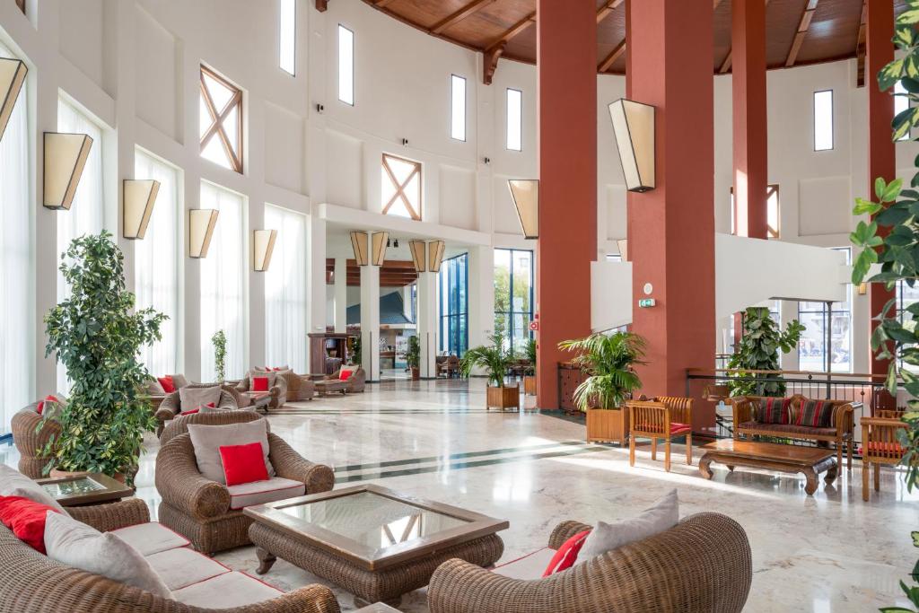 a lobby with couches and tables and windows at Sandos Papagayo in Playa Blanca