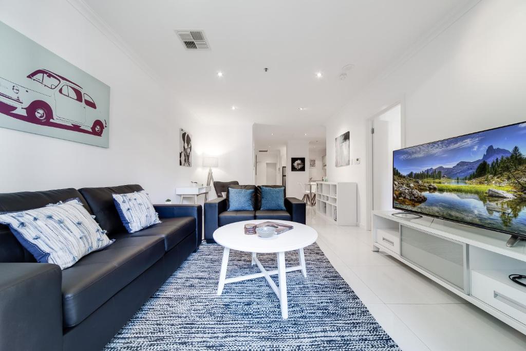 uma sala de estar com um sofá, uma televisão e uma mesa em York Apartments on Grenfell em Adelaide