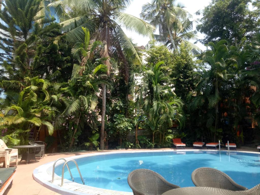 a swimming pool in a resort with chairs and palm trees at Wilson Ayurvedic Beach Resorts in Kovalam