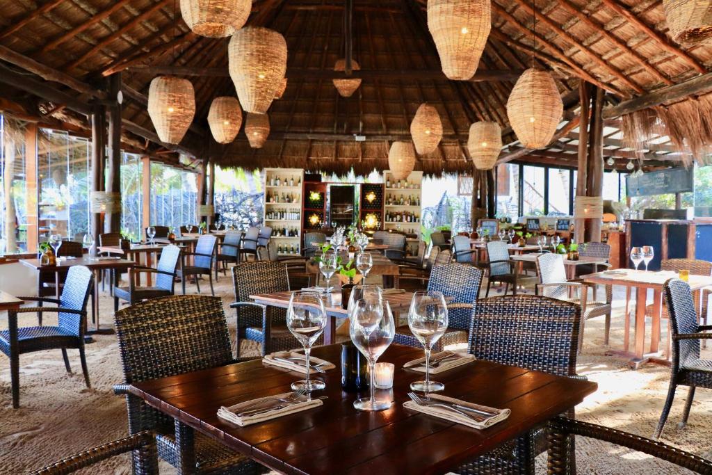 a dining room with tables and chairs and chandeliers at The Beach Tulum Hotel in Tulum