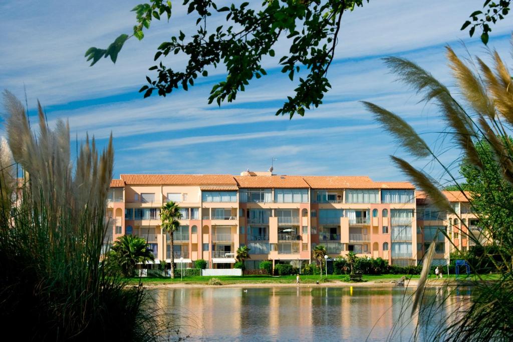 un bâtiment à côté d'un plan d'eau dans l'établissement Vacancéole - La Baie des Anges, au Cap d'Agde