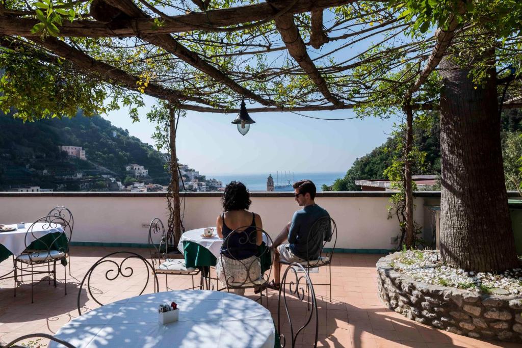 two people sitting at a picnic table outside at Hotel Relais Villa Annalara in Amalfi