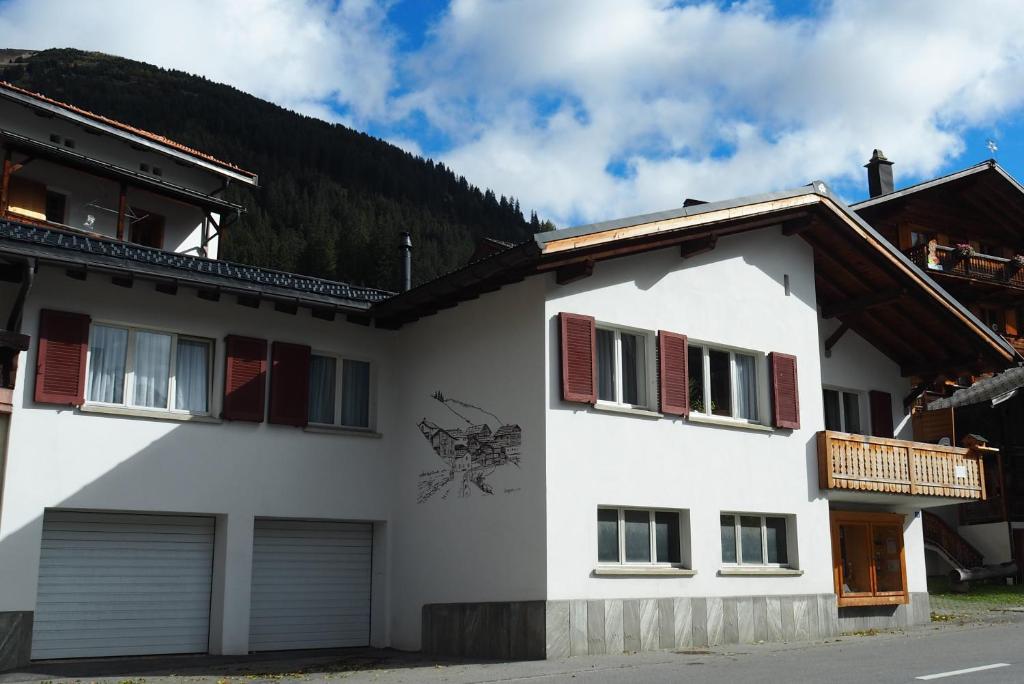 un edificio blanco con persianas rojas. en BnB Ernesto Langwies - NOT Davos, en Langwies