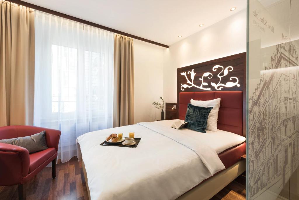 a hotel room with a bed and a red chair at Hotel Scheuble in Zürich