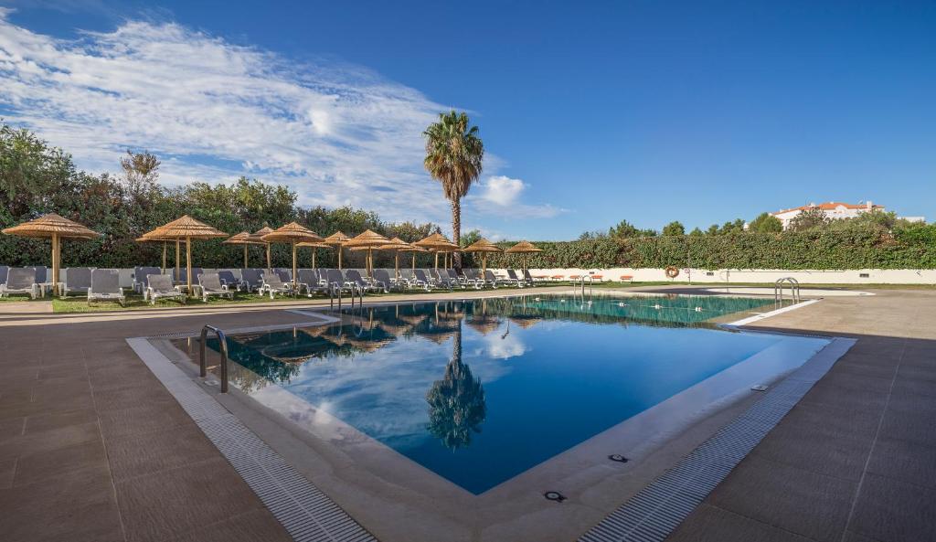 a swimming pool with chairs and umbrellas at Interpass Vau Hotel Apartamentos in Portimão