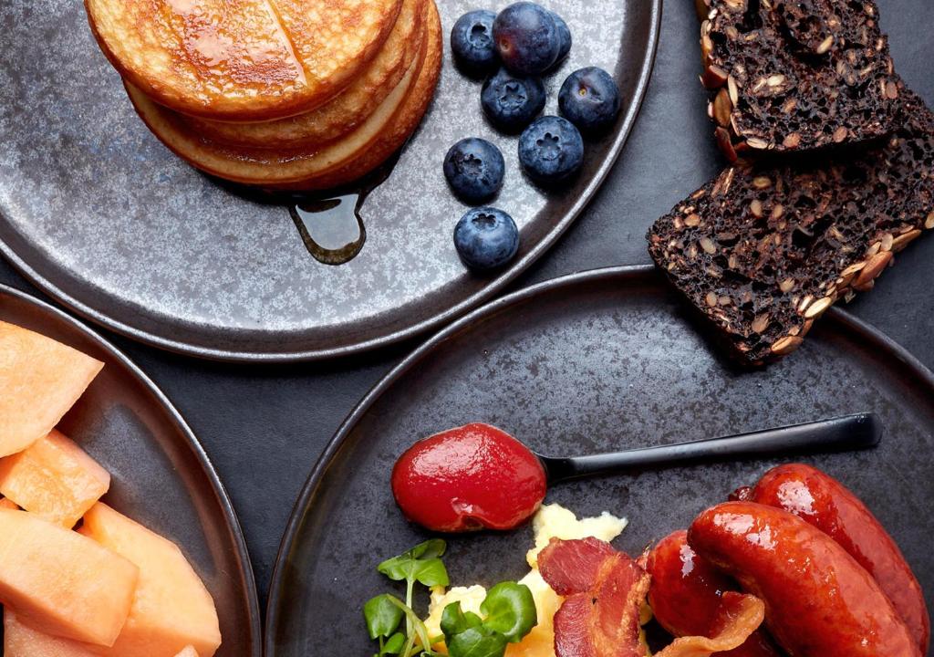 a table with plates of food with toast and fruit at Charlottehaven in Copenhagen