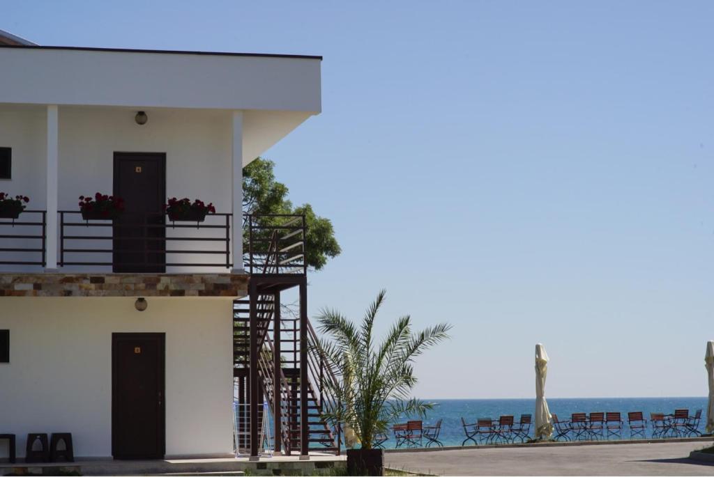 曼加利亞的住宿－Bungalouri La Mare*** Saturn，一座白色的建筑,设有海边的楼梯