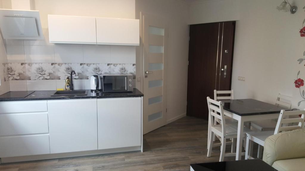 una cocina con armarios blancos y una mesa pequeña con mesa en Apartament Centrum 2, en Mikołajki