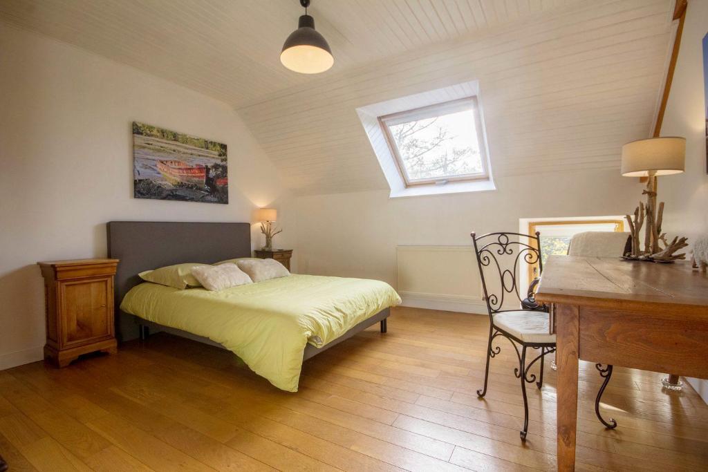 a bedroom with a bed and a desk and a window at Les Jardins de Coët-Kra in Plaudren