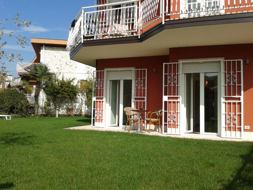 a red house with a balcony and a lawn at Appartamento Villa Ivan in Lazise