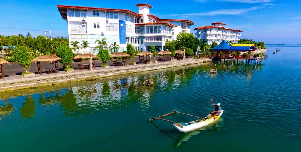 a man in a boat in the water in front of buildings at Hotel East Lagoon in Batticaloa