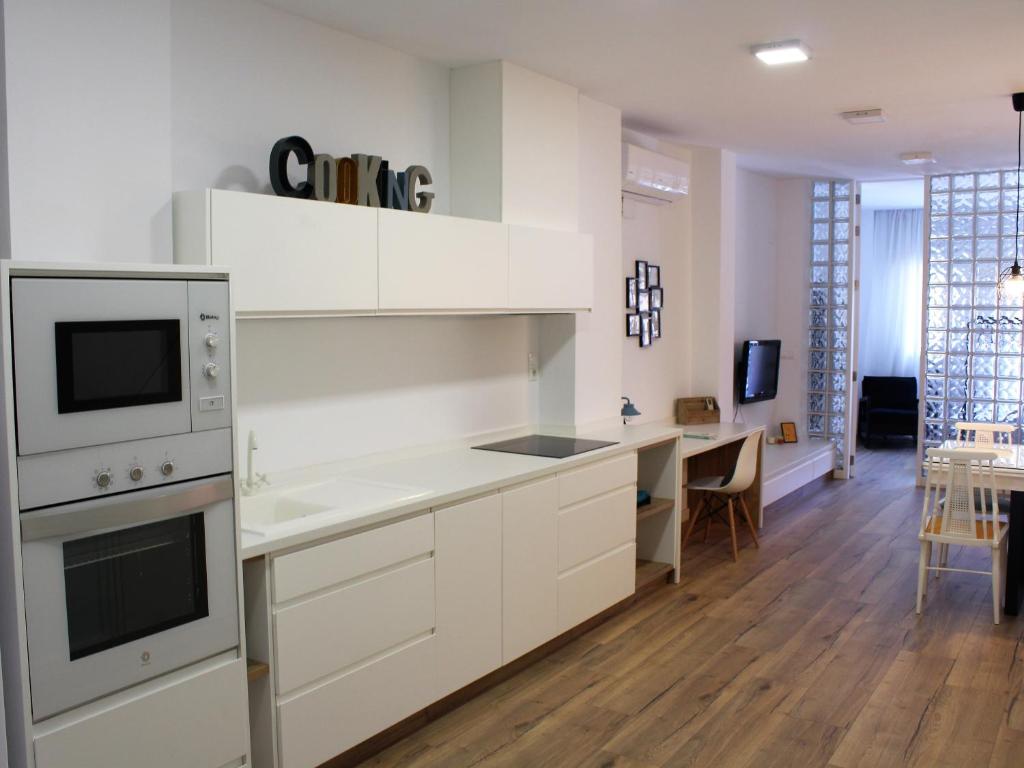バレンシアにあるModerno Apartamento en la playa del Cabanyalの白いキャビネット付きのキッチン、ダイニングルーム