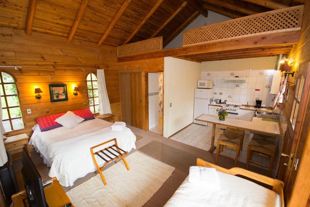 a bedroom with a large bed and a kitchen at Cabañas Playa Linda in Pucón