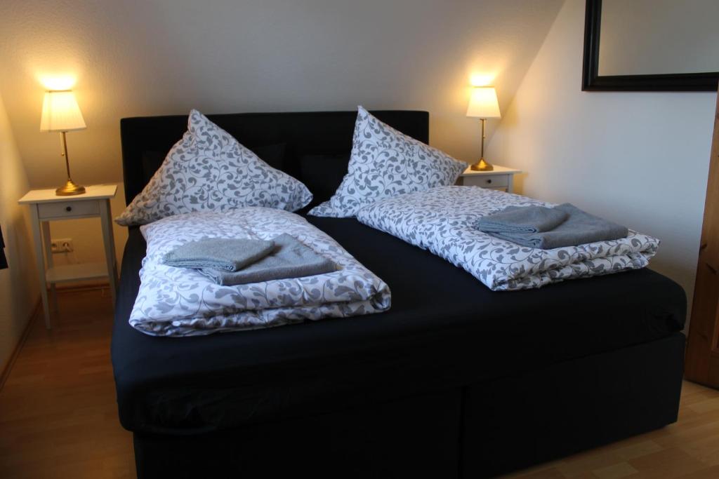 a black bed with two pillows on it with two lamps at Haus Fischkutter in Leezdorf
