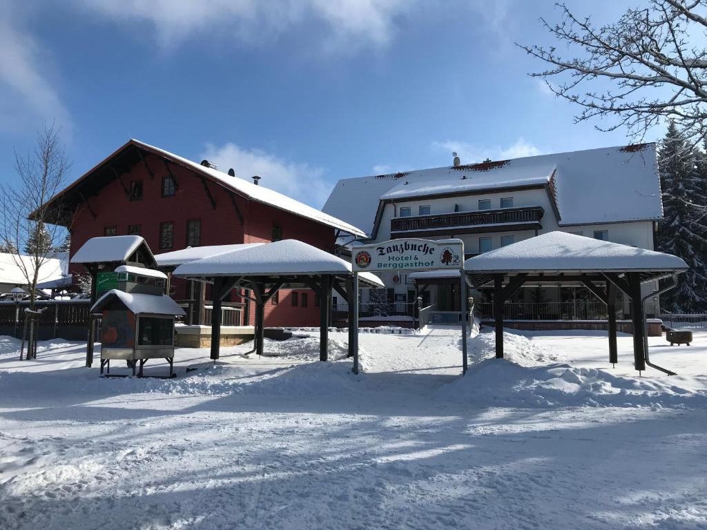 um edifício com telhados cobertos de neve na neve em Hotel und Berggasthof Tanzbuche em Friedrichroda