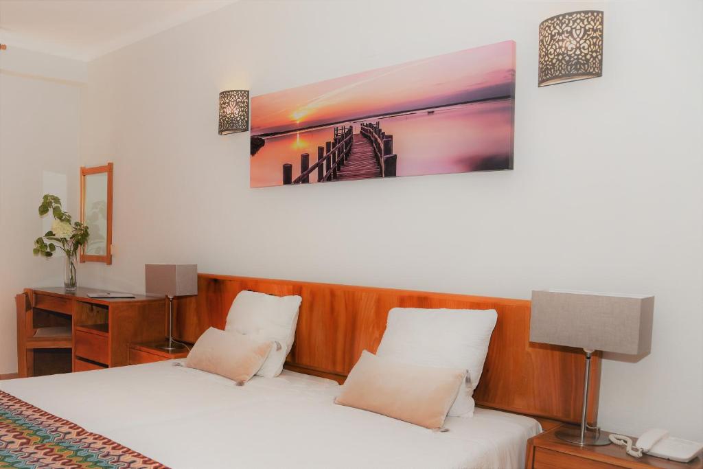 a bedroom with two beds and a painting on the wall at Apartamentos Turisticos Lindomar in Armação de Pêra