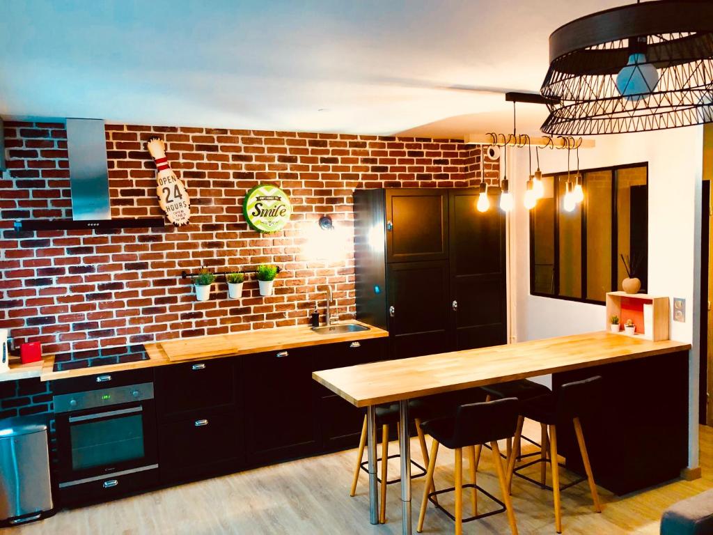 een keuken met een houten tafel en een bakstenen muur bij La charmeraie in Compiègne