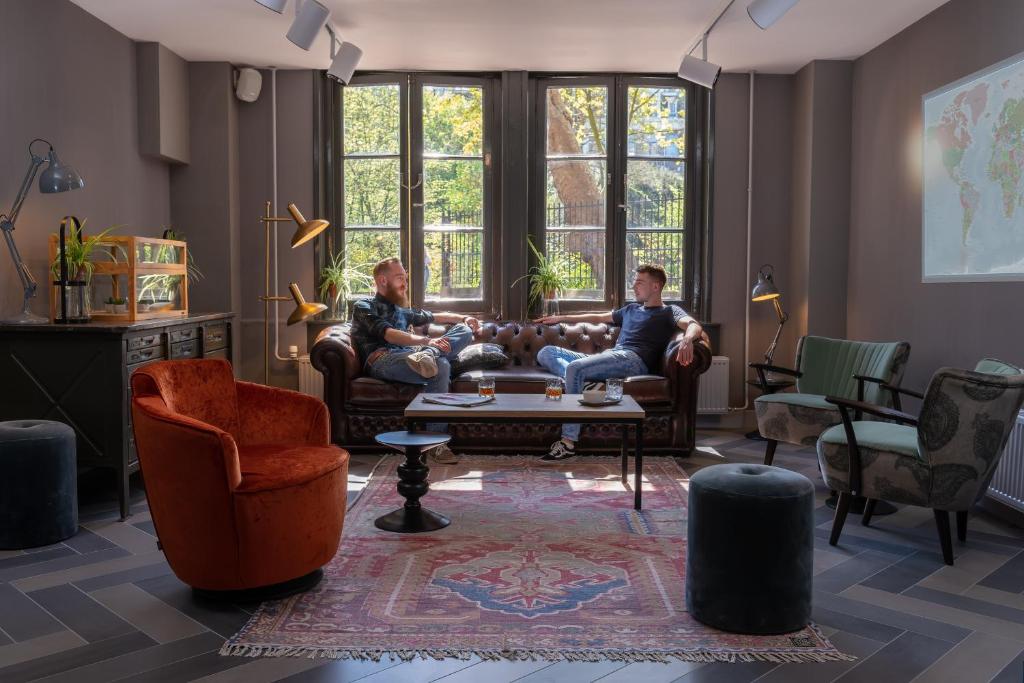 two men sitting on a couch in a living room at Stayokay Hostel Amsterdam Vondelpark in Amsterdam