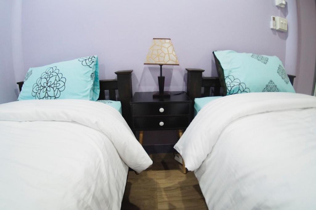 a bedroom with two beds and a table with a lamp at Pan Din Boutique Guest House in Phra Nakhon Si Ayutthaya