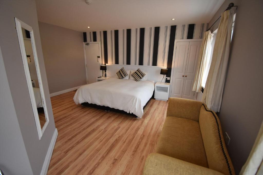 ポートラッシュにあるAaranmore Lodge Guest Houseのベッドルーム(白いベッド1台、ソファ付)
