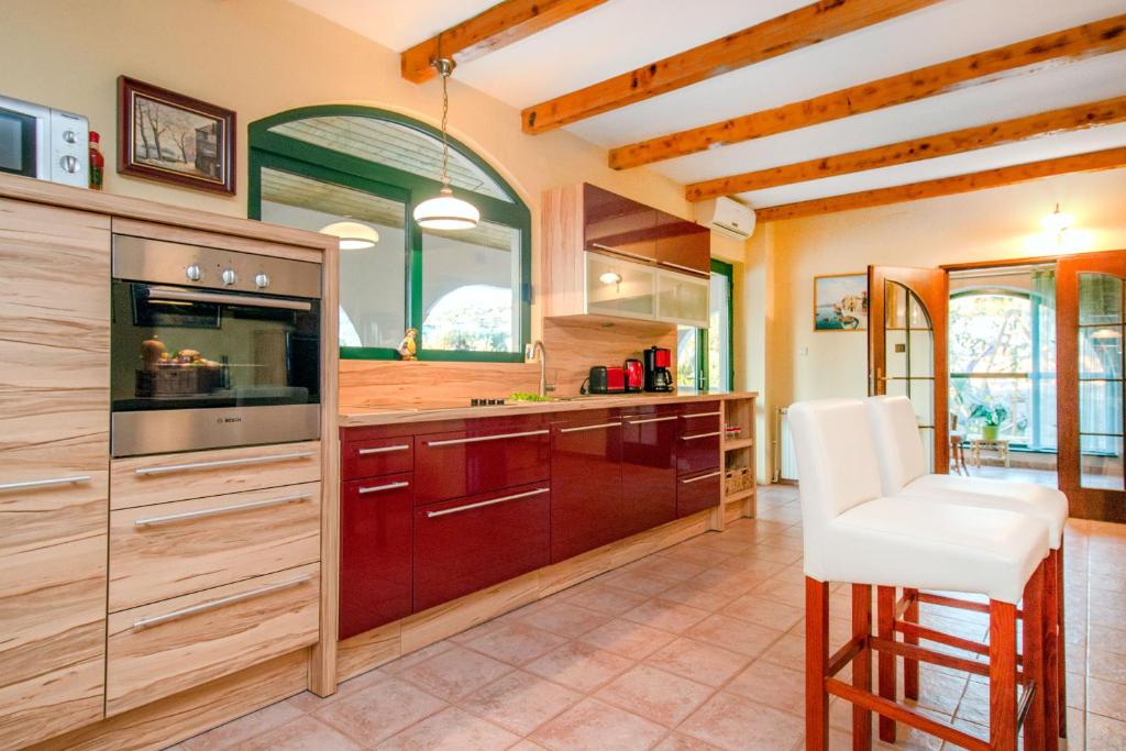 a kitchen with wooden cabinets and a white stool at Villa Sonnhaus in Marina