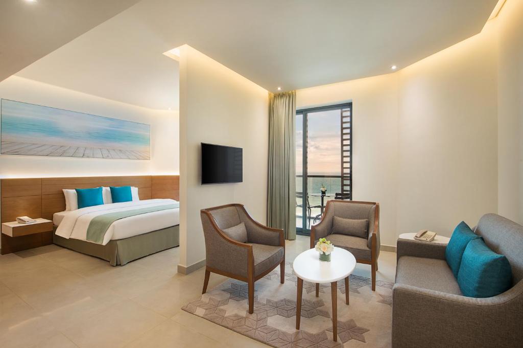 a hotel room with a bed and a table and chairs at Wyndham Garden Ajman Corniche in Ajman 